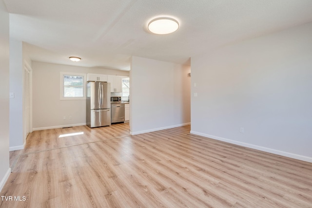 unfurnished living room featuring light wood-type flooring and baseboards