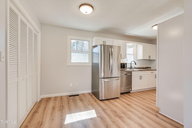 kitchen featuring light wood-type flooring, plenty of natural light, visible vents, and stainless steel appliances