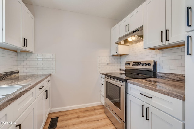 kitchen with stainless steel electric range oven, white cabinets, light wood-type flooring, under cabinet range hood, and baseboards