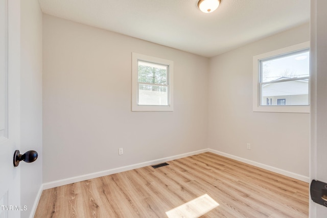 unfurnished room featuring wood finished floors, visible vents, and baseboards