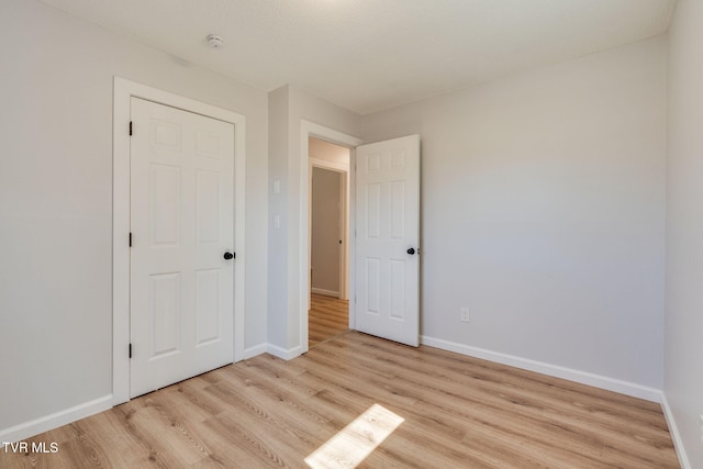 unfurnished bedroom with light wood-style flooring and baseboards