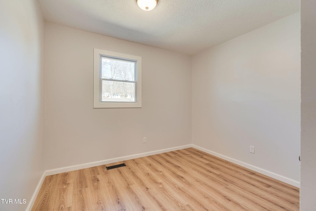 unfurnished room featuring baseboards, a textured ceiling, visible vents, and wood finished floors