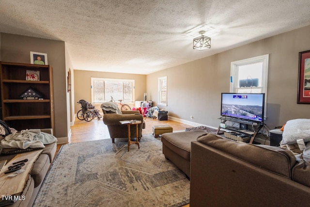 living area with a textured ceiling, baseboards, and wood finished floors