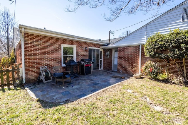 back of house featuring a patio area, a lawn, and brick siding