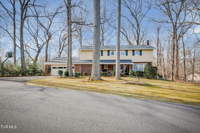 view of front of home with a garage, brick siding, driveway, a front lawn, and a chimney