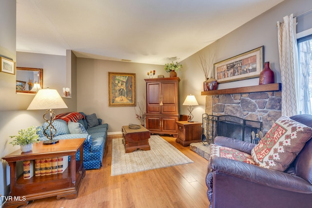 living area featuring light wood-style flooring, a fireplace, and baseboards