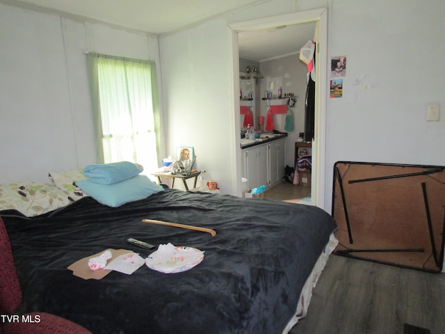 bedroom featuring crown molding, ensuite bath, and wood finished floors