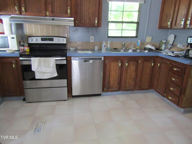 kitchen with brown cabinets, visible vents, appliances with stainless steel finishes, a sink, and under cabinet range hood