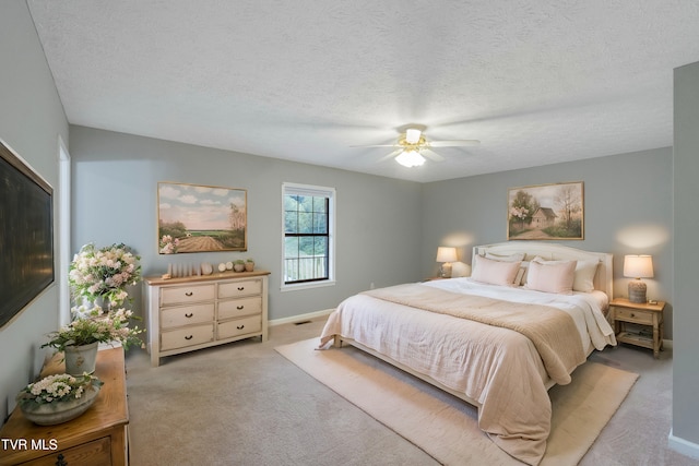 bedroom with ceiling fan, light carpet, and a textured ceiling