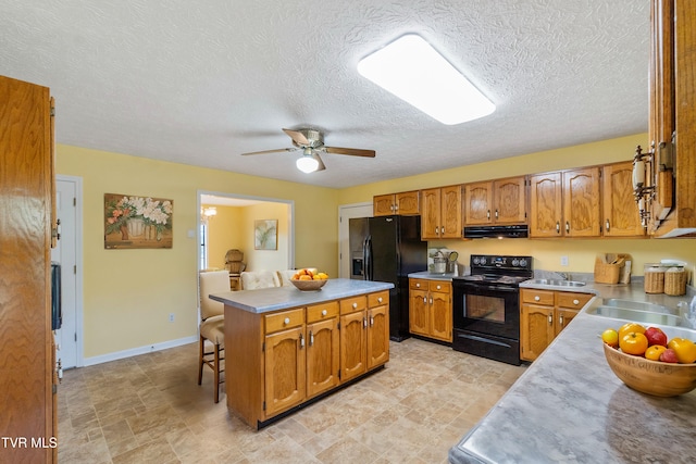 kitchen featuring a kitchen breakfast bar, sink, black appliances, and a center island