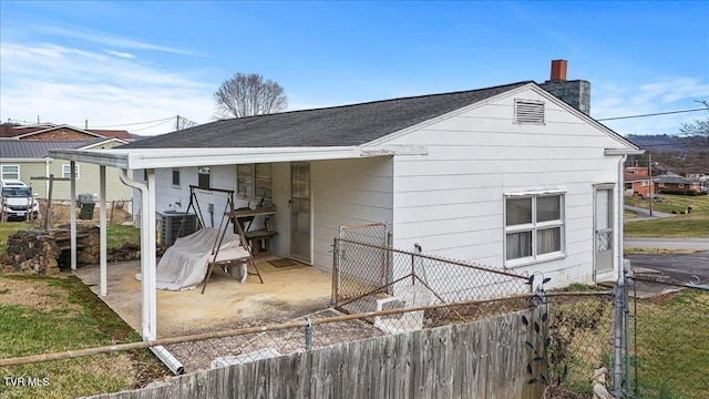 exterior space featuring roof with shingles, central AC unit, a chimney, and fence