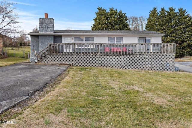 rear view of house featuring a chimney, a yard, and a deck