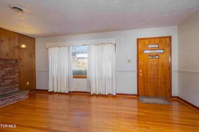 interior space featuring light wood-style flooring, visible vents, baseboards, a textured ceiling, and a fireplace