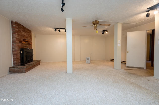 below grade area featuring track lighting, light colored carpet, a textured ceiling, and ceiling fan