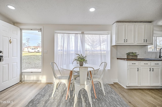 dining space with light hardwood / wood-style floors and a textured ceiling