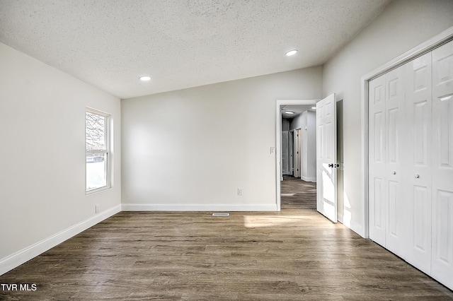 unfurnished bedroom with dark hardwood / wood-style floors, a textured ceiling, and a closet