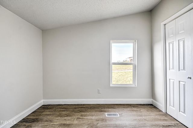 spare room with a textured ceiling and hardwood / wood-style floors