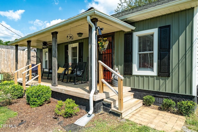 property entrance featuring covered porch, board and batten siding, fence, and a ceiling fan