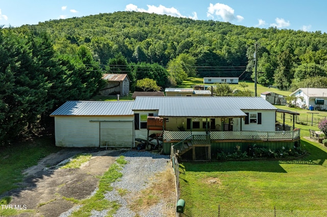 view of front facade featuring a wooded view, metal roof, driveway, and a garage