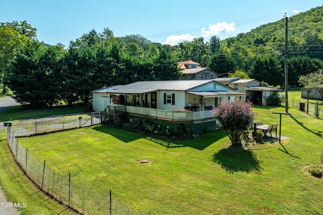 view of front facade featuring metal roof, fence, and a front lawn