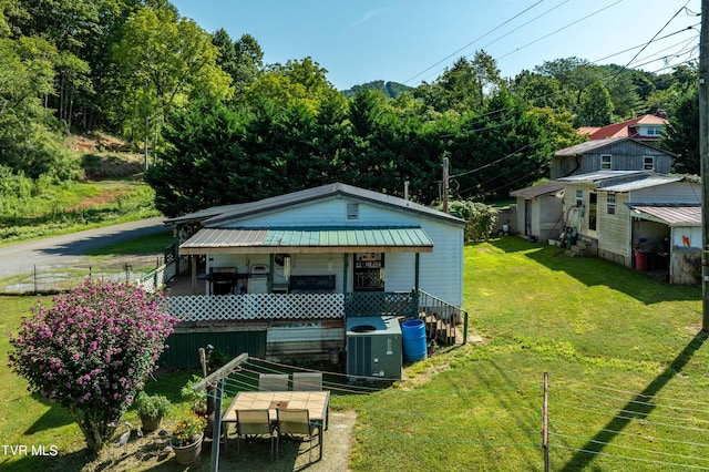 view of front of property featuring metal roof, covered porch, a front lawn, and cooling unit