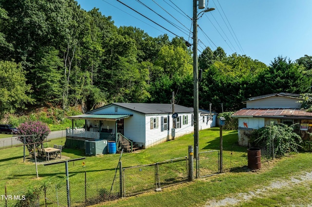 view of front of house featuring a gate, fence, metal roof, and a front lawn