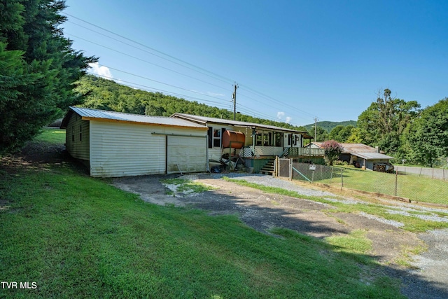 view of front facade featuring fence, driveway, a garage, metal roof, and a front yard