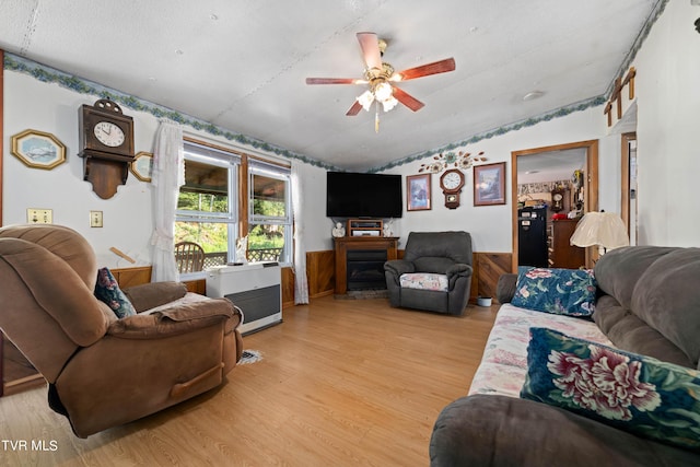 living room with heating unit, a ceiling fan, light wood finished floors, a fireplace, and lofted ceiling