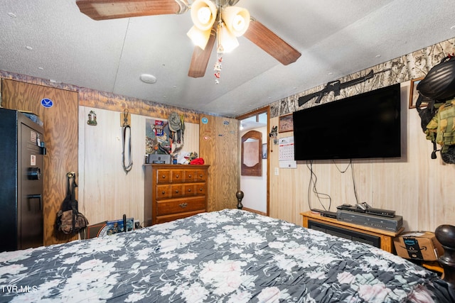 bedroom featuring arched walkways, black fridge, wood walls, and a textured ceiling