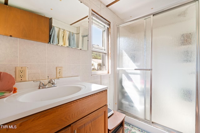 bathroom featuring vanity, tile walls, decorative backsplash, and a shower stall