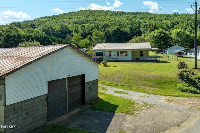 exterior space with a view of trees, a porch, metal roof, and a yard