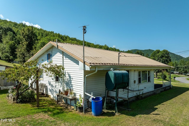 rear view of property featuring metal roof and a yard