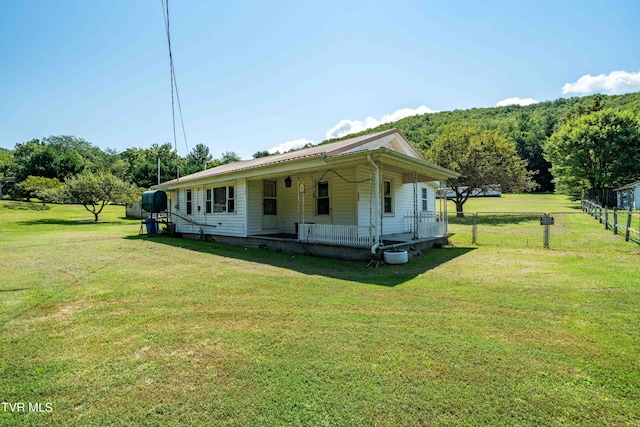 view of front facade featuring metal roof, a front yard, and fence