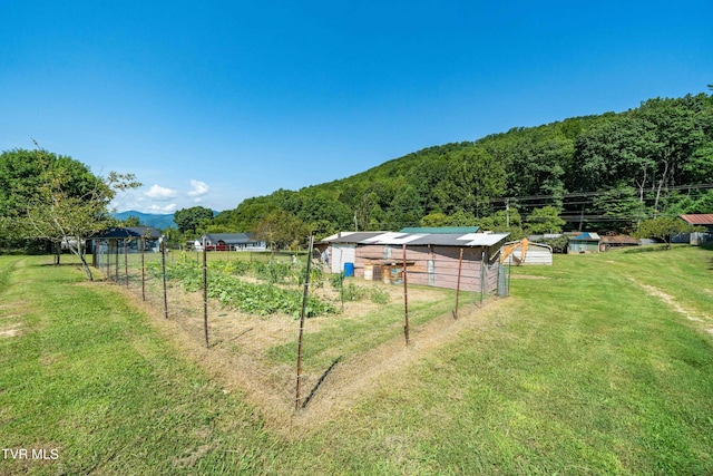 view of yard featuring fence, a garden, a rural view, and a mountain view