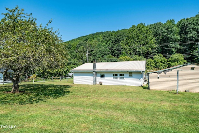 exterior space with metal roof, fence, and a lawn