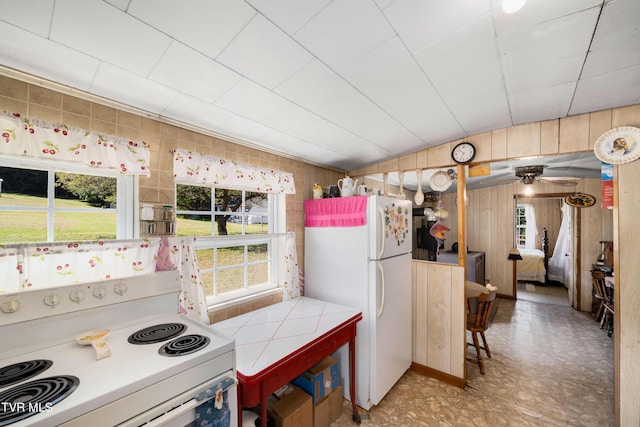 kitchen featuring a wealth of natural light, tile countertops, vaulted ceiling, and white appliances