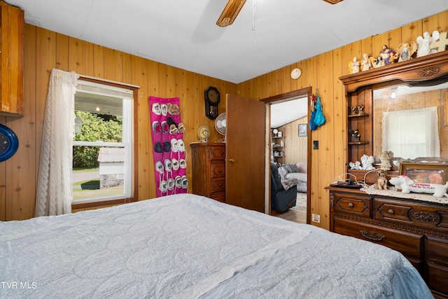 bedroom with ceiling fan and wood walls