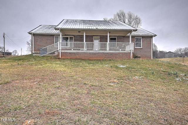 view of front facade featuring a porch, a standing seam roof, brick siding, and a front lawn