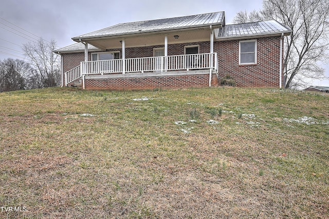 view of front facade featuring metal roof, a porch, a front lawn, and brick siding