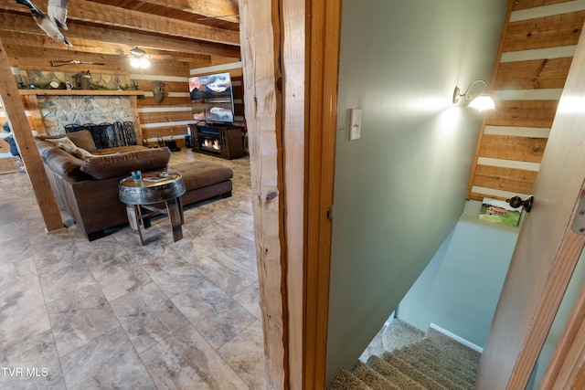 interior space featuring wood walls, wood ceiling, a fireplace, and beam ceiling