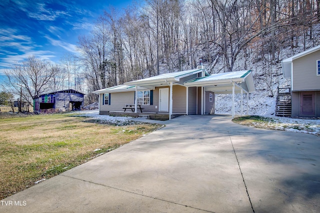 view of front of property featuring a carport, concrete driveway, metal roof, and a front lawn