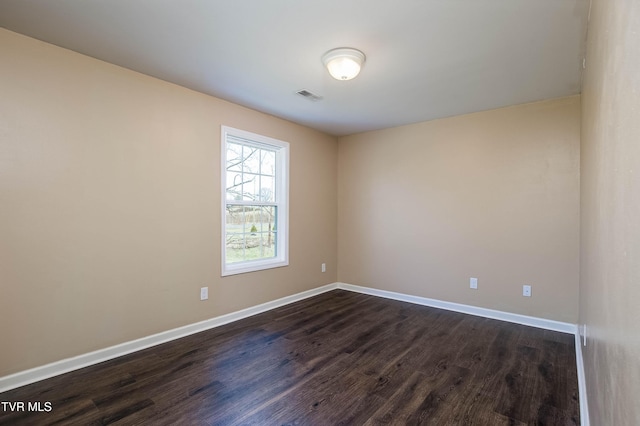 unfurnished room with baseboards, visible vents, and dark wood finished floors