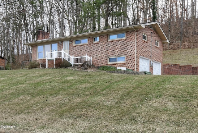 view of front facade featuring a garage, brick siding, a chimney, and a front yard