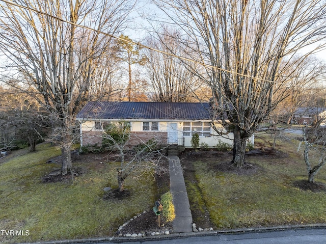 single story home featuring metal roof, brick siding, and a front lawn