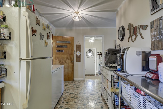 kitchen featuring stone finish flooring, ornamental molding, white cabinets, and freestanding refrigerator