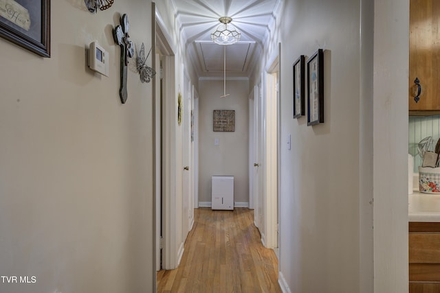 corridor featuring attic access, light wood-style floors, ornamental molding, and baseboards