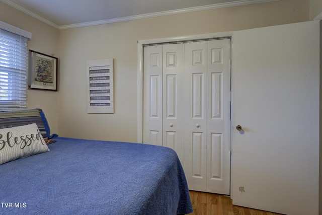 bedroom with ornamental molding, a closet, and wood finished floors