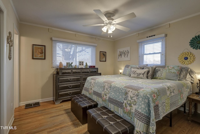 bedroom featuring crown molding, visible vents, light wood-style floors, a ceiling fan, and baseboards