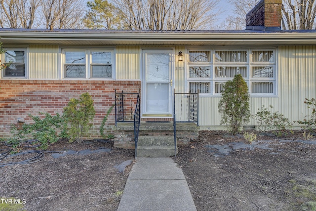 entrance to property featuring brick siding and a chimney