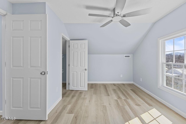 bonus room featuring light wood-style floors, a healthy amount of sunlight, vaulted ceiling, and baseboards